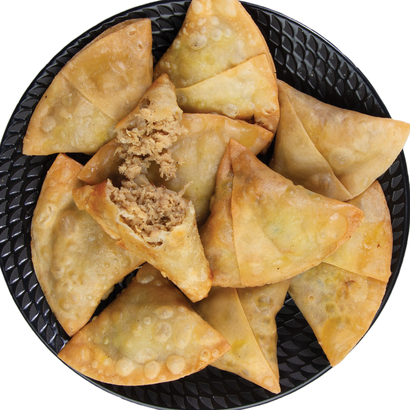 Chicken samosas on a black plate with one open to reveal the filling.
