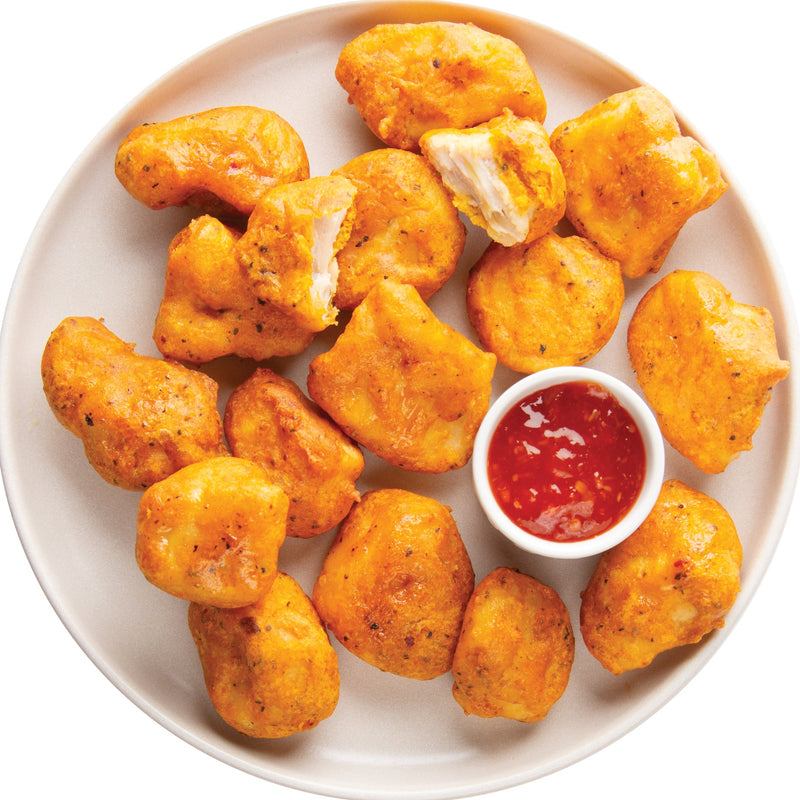 Plate of golden-brown chicken nuggets with a small bowl of red sauce